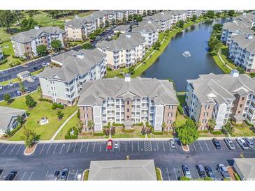 Expansive aerial view of condo community with lake, fountain, manicured lawns and abundant parking spaces at 4821 Luster Leaf Circle # 202, Myrtle Beach, SC 29577