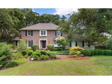 Charming brick home featuring mature landscaping, a manicured lawn, and a welcoming front entrance at 571 Fernwood Rd., Murrells Inlet, SC 29576