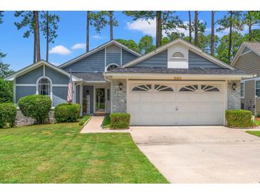 Charming home featuring a two-car garage, manicured lawn and low foundation shrubbery at 890 Knoll Dr., Little River, SC 29566