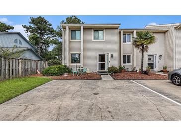 Inviting townhouse featuring a neatly landscaped front yard, a patio set, and convenient parking space at 951 Plantation Dr. # F1, Little River, SC 29566