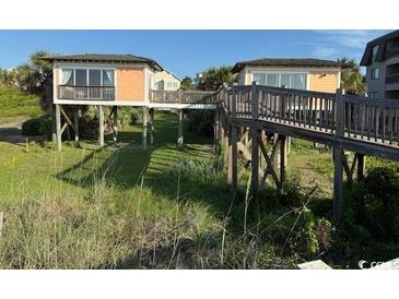 Charming beachfront cottages connected by wooden walkway, surrounded by lush greenery at 5732 N Ocean Blvd., Myrtle Beach, SC 29577