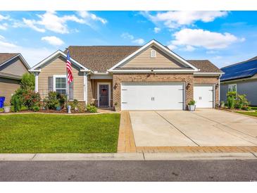 Inviting single-story home boasts a well-manicured lawn and an attached two-car garage, American flag, and brick accents at 1941 La Playa Dr., Myrtle Beach, SC 29588