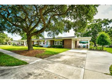 Charming brick home features a manicured front yard, large tree, and covered parking at 3602 Magnolia St. # 3602, Myrtle Beach, SC 29577