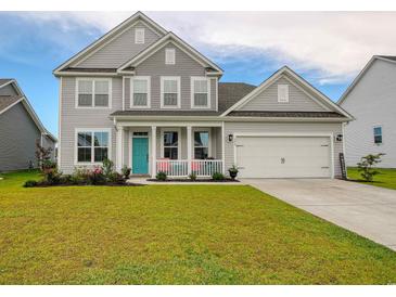 Charming two-story home showcasing a well-manicured lawn, welcoming front porch, and delightful curb appeal at 376 Mikita Dr., Surfside Beach, SC 29575