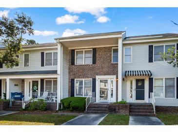 Charming townhome featuring a brick facade, black shutters, and inviting front entrances under a blue and cloudy sky at 4115 Little River Rd. # 1-E, Myrtle Beach, SC 29577