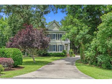 Charming two-story home with lush landscaping, mature trees, and a long driveway leading to the house at 100 Brookgreen Trace Pl., Pawleys Island, SC 29585