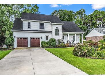 Charming two-story home with a well-manicured lawn, two-car garage, and inviting front porch at 1064 Links Rd., Surfside Beach, SC 29575