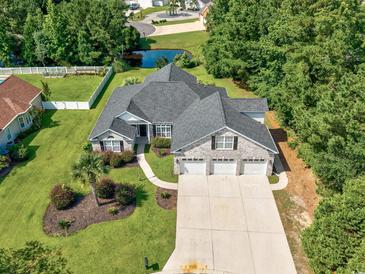Stunning aerial view of a home with a three car garage, landscaped yard, and a pond at 229 Duchess Ct., Myrtle Beach, SC 29588