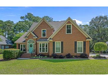 Charming two-story brick home with a well-manicured lawn and a welcoming blue front door and black shutters at 3975 River Hills Dr., Little River, SC 29566
