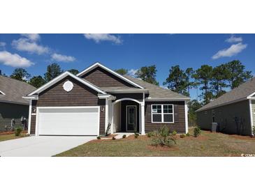 Charming brown house featuring a white garage door, complemented by well-maintained landscaping at 1239 Maxwell Dr., Little River, SC 29566