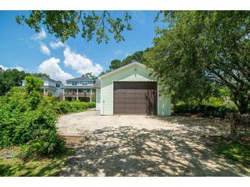 A detached garage features a brown door and light green siding, providing secure parking or storage at 127 Brown Pelican Loop, Pawleys Island, SC 29585