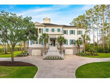 Stately home with well manicured yard, palm trees, symmetrical facade and white exterior with blue shutters at 288 Tipperary Pl., Pawleys Island, SC 29585