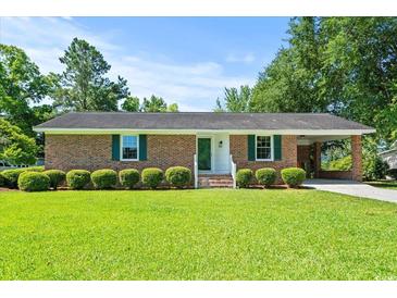 Charming brick home features a well-manicured front lawn and classic design, enhanced by lush green landscaping at 324 Camellia Ave., Marion, SC 29571