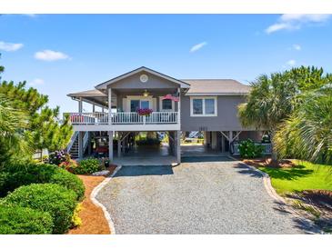 Charming coastal home with a stilt foundation, lush landscaping, and a spacious driveway at 401 Marlin St., Sunset Beach, NC 28468