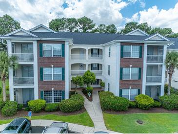 Attractive multi-story condo building with brick accents, white trim, well-maintained landscaping, and a walkway at 468 River Oak Dr. # 66D, Myrtle Beach, SC 29579