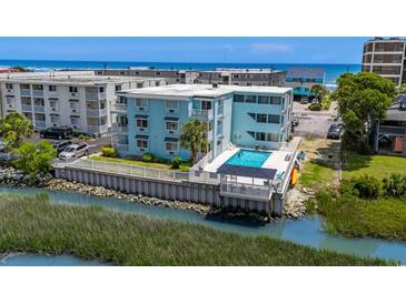 Aerial view of a light-blue multifamily building with a pool overlooking a waterway and the ocean at 6301 N Ocean Blvd. # 2B, North Myrtle Beach, SC 29582