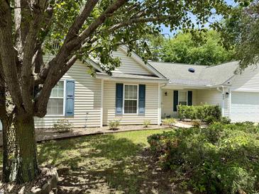 Charming single-story home with light siding, blue shutters, and mature landscaping at 233 Melody Gardens Dr., Surfside Beach, SC 29575