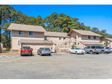 View of the condo complex with beige exterior, parking lot, wooden staircases, and surrounding trees at 3015 Old Bryan Dr. # 4, Myrtle Beach, SC 29577