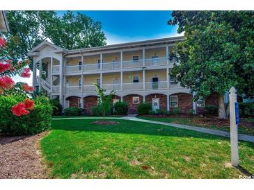 Three-story condominium building with white railings, brick accents, and lush green lawn at 695 Riverwalk Dr. # 101, Myrtle Beach, SC 29579