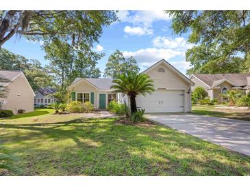 Charming one story home featuring a well-manicured lawn and a two-car garage at 83 Reef Run Rd., Pawleys Island, SC 29585
