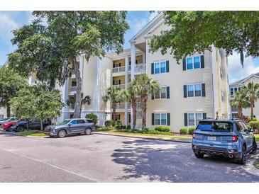 Condo building exterior with light-yellow siding, white trim, green shutters, and palm trees at 601 Hillside Dr. N # 3926, North Myrtle Beach, SC 29582