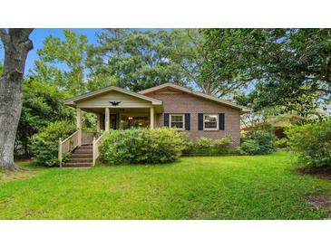 Charming brick home featuring a cozy front porch and a well-manicured lawn, surrounded by lush greenery at 1272 Park Hill Dr., Conway, SC 29526
