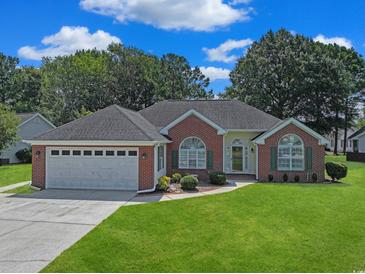 Charming brick home with a well-manicured lawn, attached two car garage, and colorful landscaping at 3888 Stillwood Dr., Myrtle Beach, SC 29588