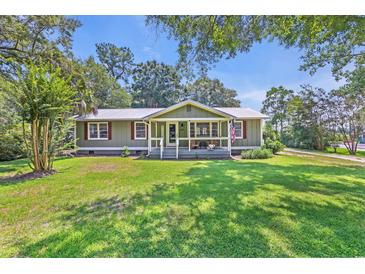 Charming single-story home with a lush green lawn, inviting front porch, and a patriotic American flag at 485 Waterford Dr., Georgetown, SC 29440