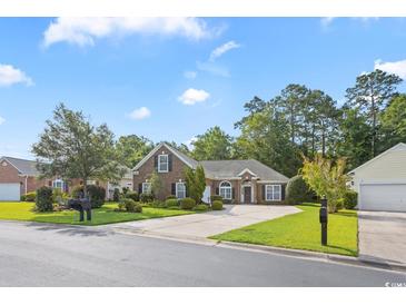 Charming brick home featuring a manicured lawn, mature trees and a paved driveway at 56 Willowbend Dr., Murrells Inlet, SC 29576
