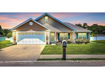 Charming single-story home featuring a manicured lawn, attached garage and inviting front porch at 1036 Macala Dr., Conway, SC 29526