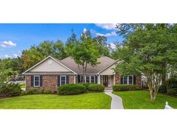 Charming brick home with manicured lawn, mature landscaping, and inviting walkway to front door at 104 Ashton Circle, Myrtle Beach, SC 29588