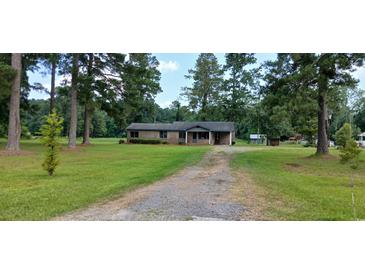 Quaint single-story brick home with a charming front porch surrounded by mature trees at 1206 French Rd, Mullins, SC 29574