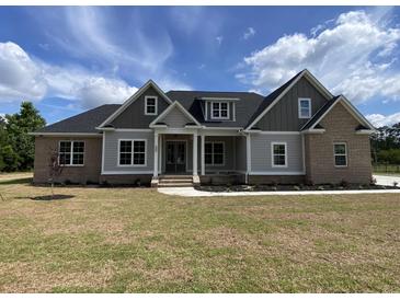 Beautiful new construction home featuring brick and grey siding, a covered porch, and professional landscaping at 140 Pottery Landing Dr., Conway, SC 29527