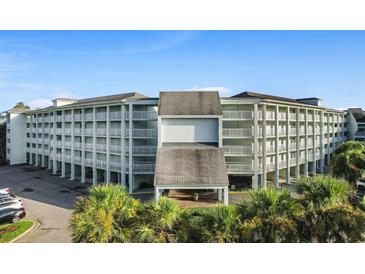 Exterior view of the multi-story condo building with a covered entrance and rows of private balconies at 14290 Ocean Hwy. # 407, Pawleys Island, SC 29585