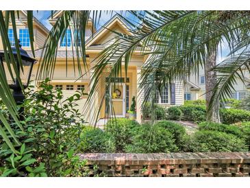 Charming home exterior featuring a well-manicured lawn and a welcoming front entrance with a yellow door and beautiful foliage at 431 Huntington Lake Circle # 80, Pawleys Island, SC 29585