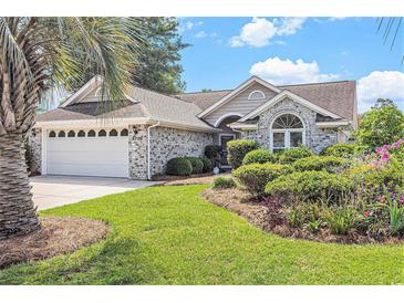 Charming home featuring a well-manicured lawn, beautiful landscaping, and an attached two-car garage at 4703 Bermuda Way, Myrtle Beach, SC 29577