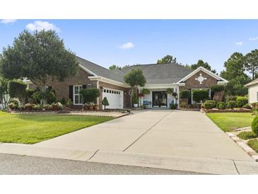 Charming brick home featuring a spacious driveway, manicured lawn, and beautifully landscaped garden beds at 5904 Bridlewood Rd., North Myrtle Beach, SC 29582