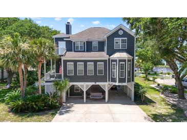 Charming two-story home with a covered front porch, a carport with swing and beautiful landscaping at 709 Triple Oak Ln., Garden City Beach, SC 29576