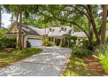 Stunning home featuring lush landscaping, a circular driveway, and a charming yellow exterior at 81 Prestwick Dr., Pawleys Island, SC 29585