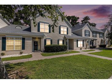 Charming townhome with green shutters and well-manicured lawn at dusk at 106 Scotch Broom Dr. # 105, Little River, SC 29566