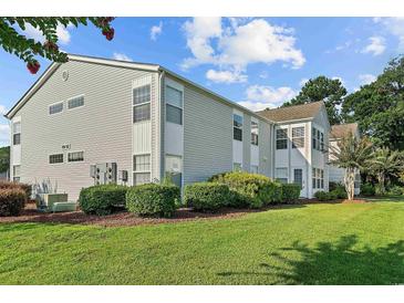 Inviting condo exterior with manicured lawn and lush landscaping under a bright, partly cloudy sky at 1931 Bent Grass Dr. # H, Surfside Beach, SC 29575