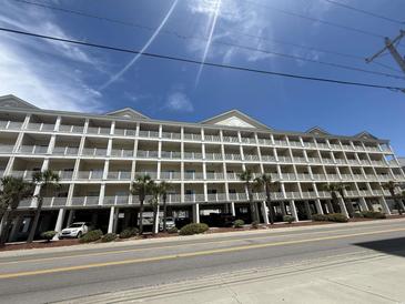 Spacious condo building with multiple floors of units, balconies, street parking, and some palm trees at 200 53Rd Ave. N # 205, North Myrtle Beach, SC 29582