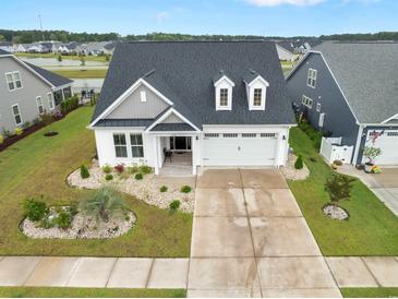 Beautiful exterior view of home with landscaped front yard, two-car garage, and a dark roof at 5087 Sundrop Ln., Little River, SC 29566