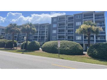 Low angle view of a well-kept condo building with palm trees and fresh landscaping on a sunny day at 812 S Ocean Blvd. # B-3, Surfside Beach, SC 29575