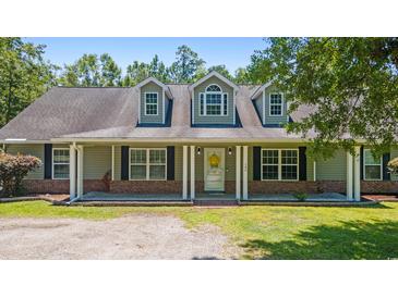 Charming home featuring a welcoming front porch with white columns and black shutters, set against a lush green lawn at 140 Pixie Dust Ct., Myrtle Beach, SC 29588