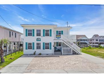 Charming two-story beach house with teal shutters and ample parking space for a relaxed coastal living experience at 329 54Th Ave. N, North Myrtle Beach, SC 29582