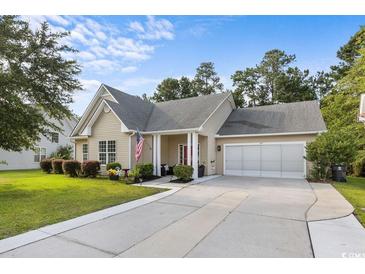 Charming single-story home featuring a well-manicured lawn, attached two-car garage, and welcoming front porch at 409 Cypress View Ave., Little River, SC 29566