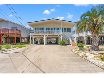 Coastal home with a large driveway, covered parking, and a white exterior with blue accents at 325 N 58Th Ave. N, North Myrtle Beach, SC 29582