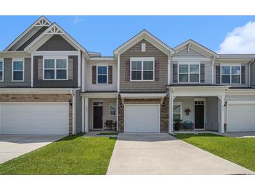 Charming townhomes featuring a mix of siding and brick accents, complemented by well-manicured lawns and a bright sky at 4051 Mclamb Ave. # 4051, Little River, SC 29566