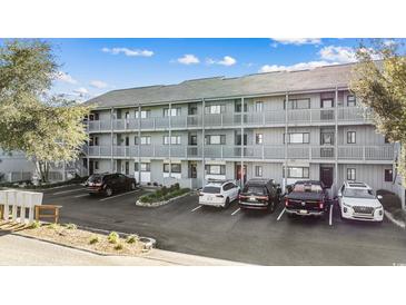 Three-story condo building with gray siding, multiple balconies, and convenient parking spaces at 7700 Porcher Dr. # 3207, Myrtle Beach, SC 29572